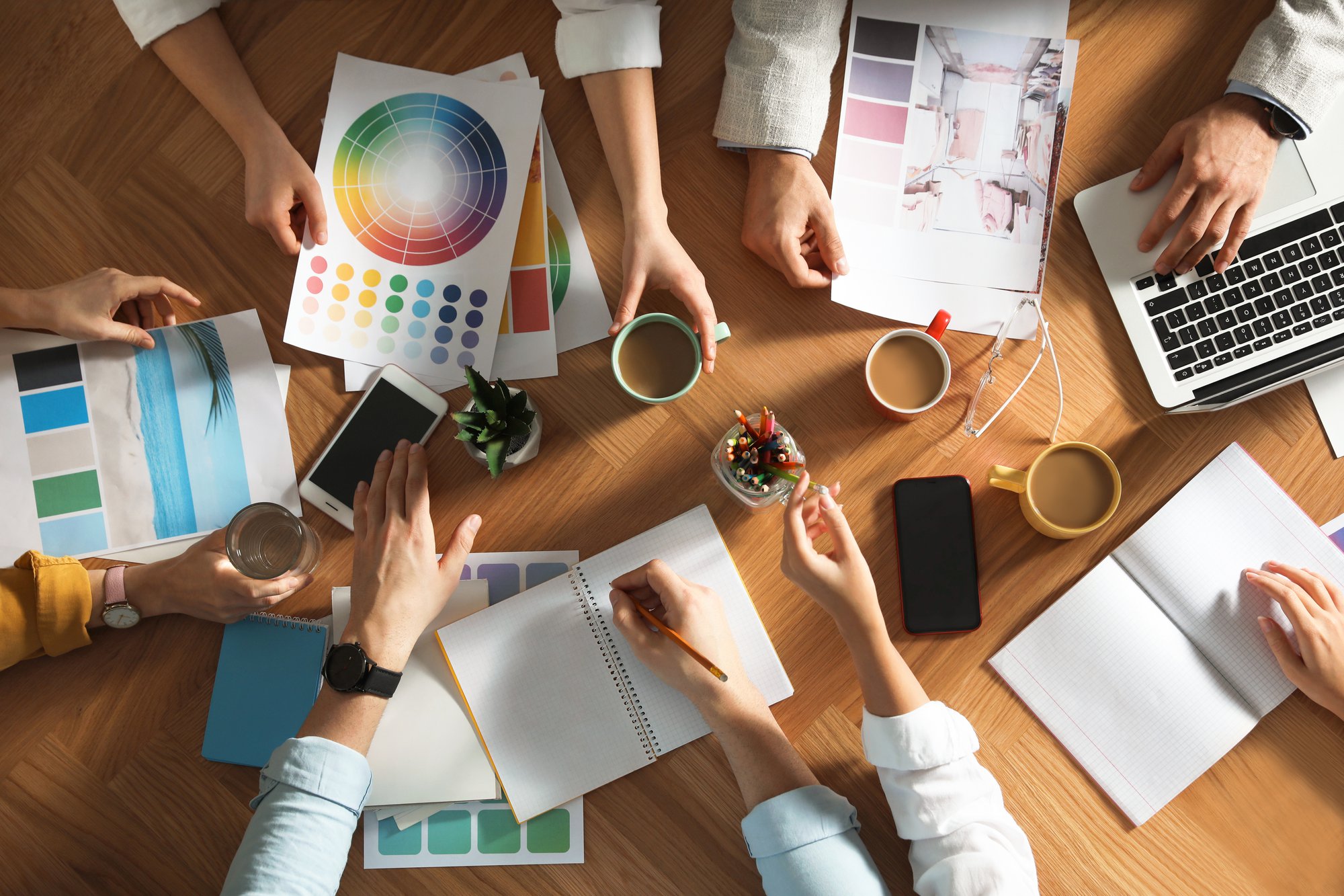 Team of professional designers working together at table, top view